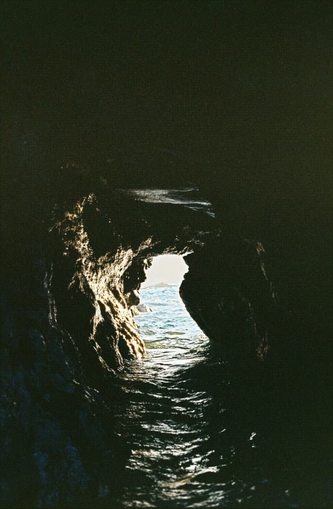 a dark sea cave opening onto sunlit water